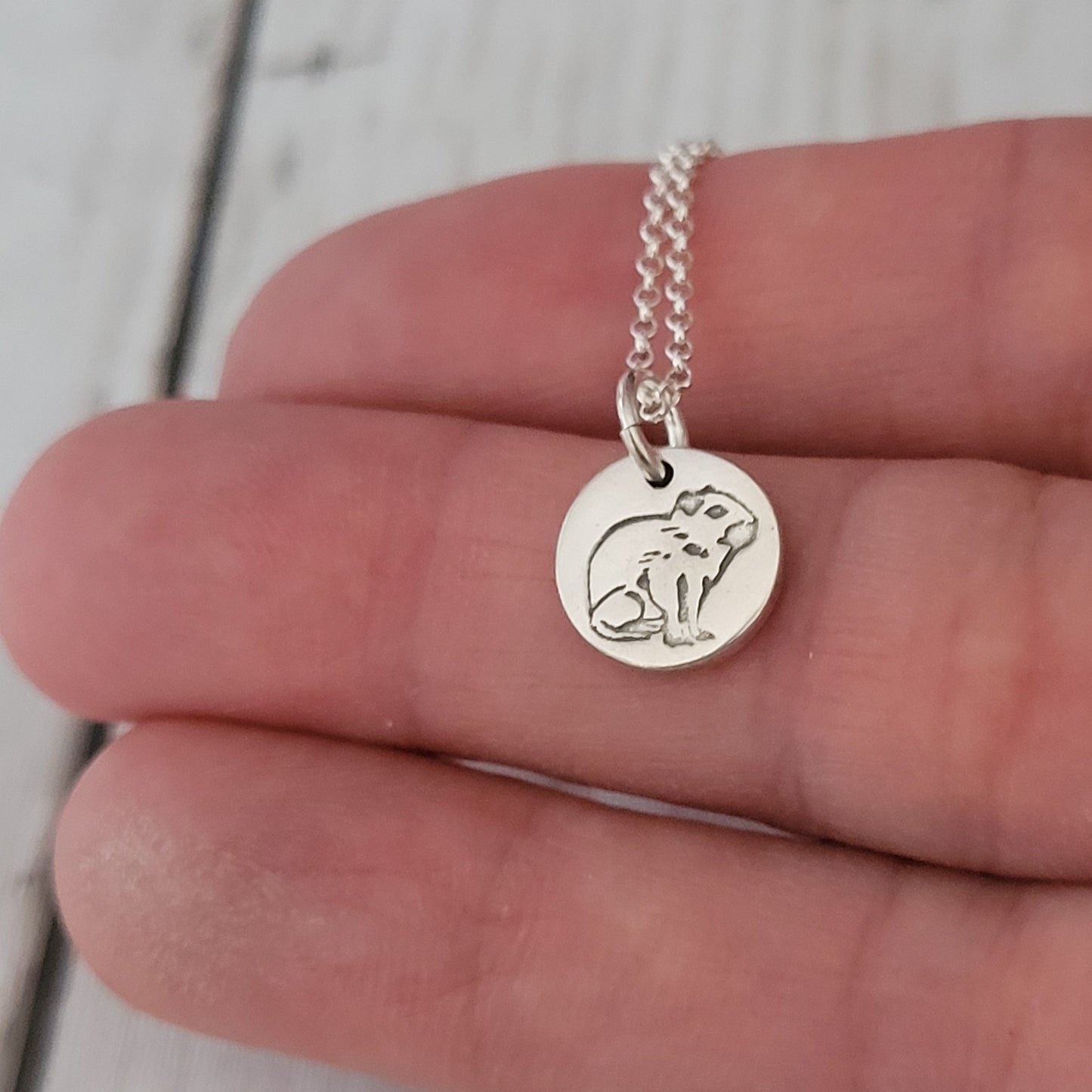 tiny 1cm capybara pendant being held in hand