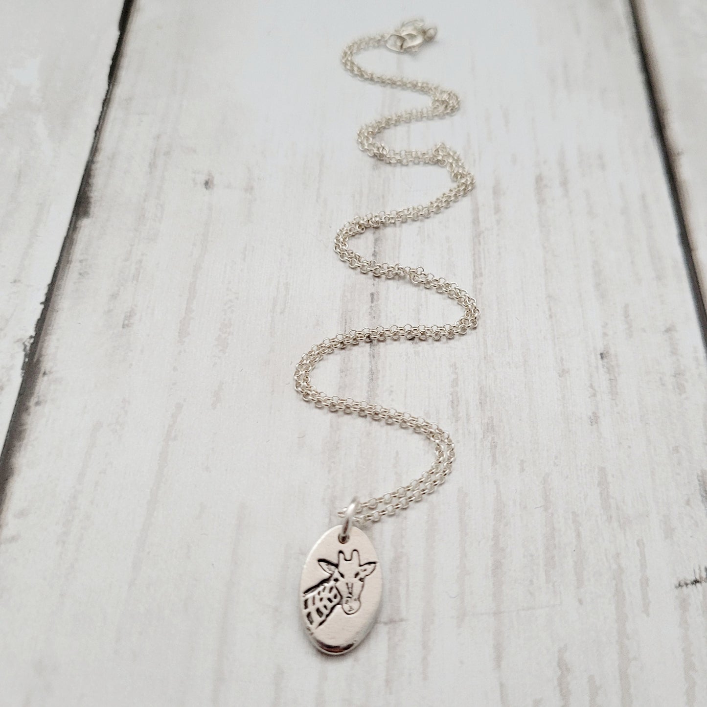 Silver necklace with a pendant on a light wooden surface