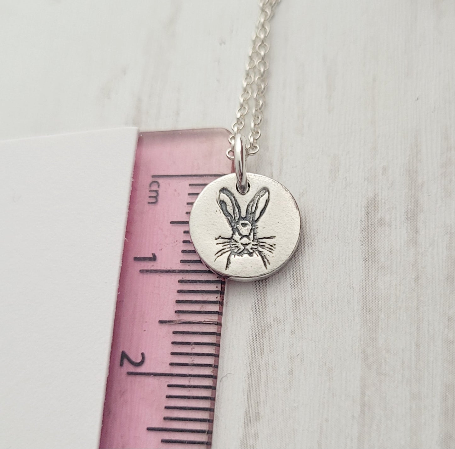 hare pendant against pink ruler