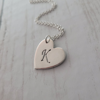 Heart-shaped silver pendant with a design on a light gray surface