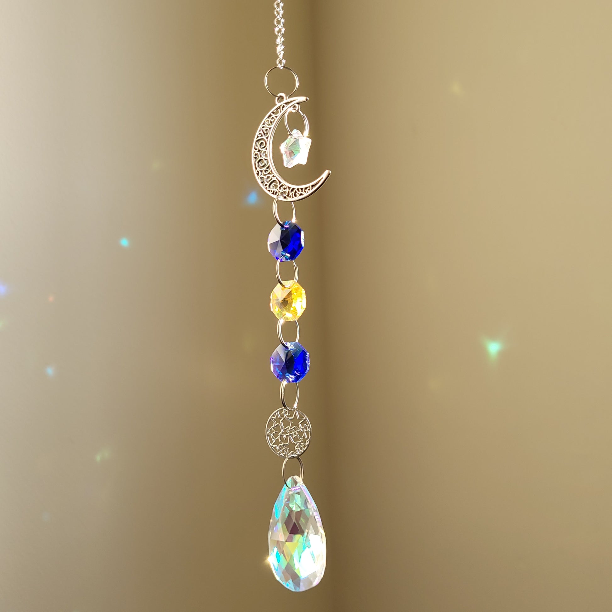 moon and star suncatcher with colourful blue and yellow crystals on a beige background