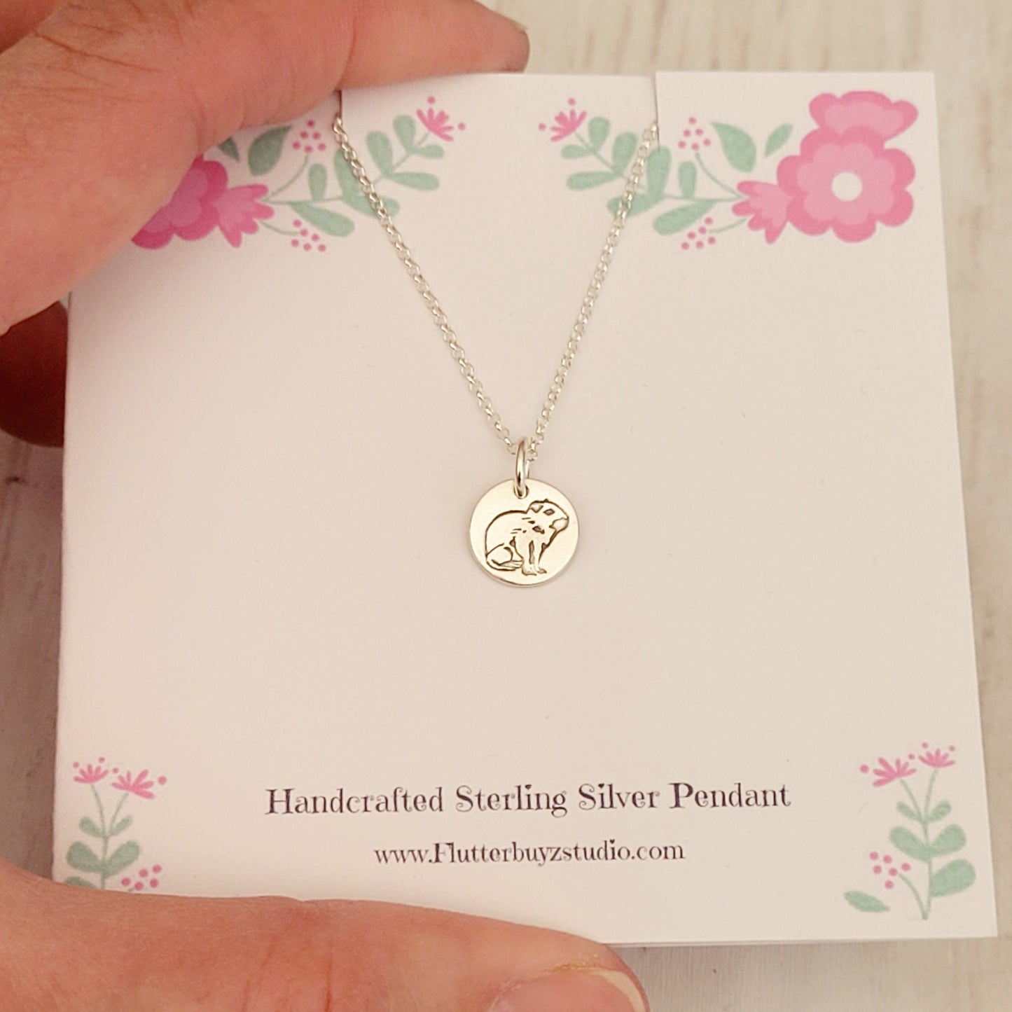 capybara necklace on pink flower presentation card