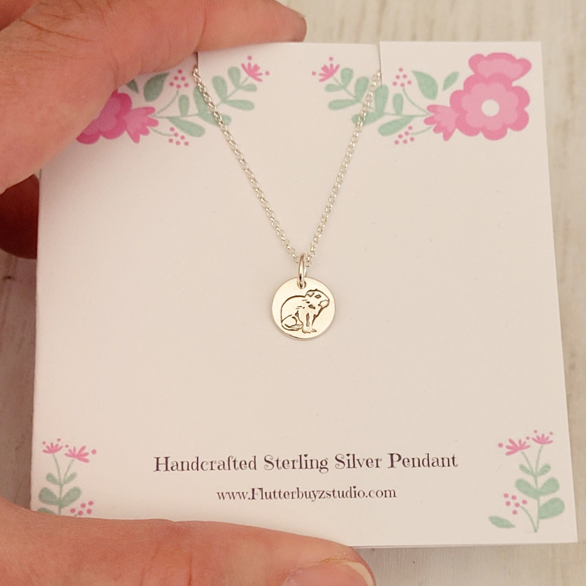 capybara necklace on pink flower presentation card