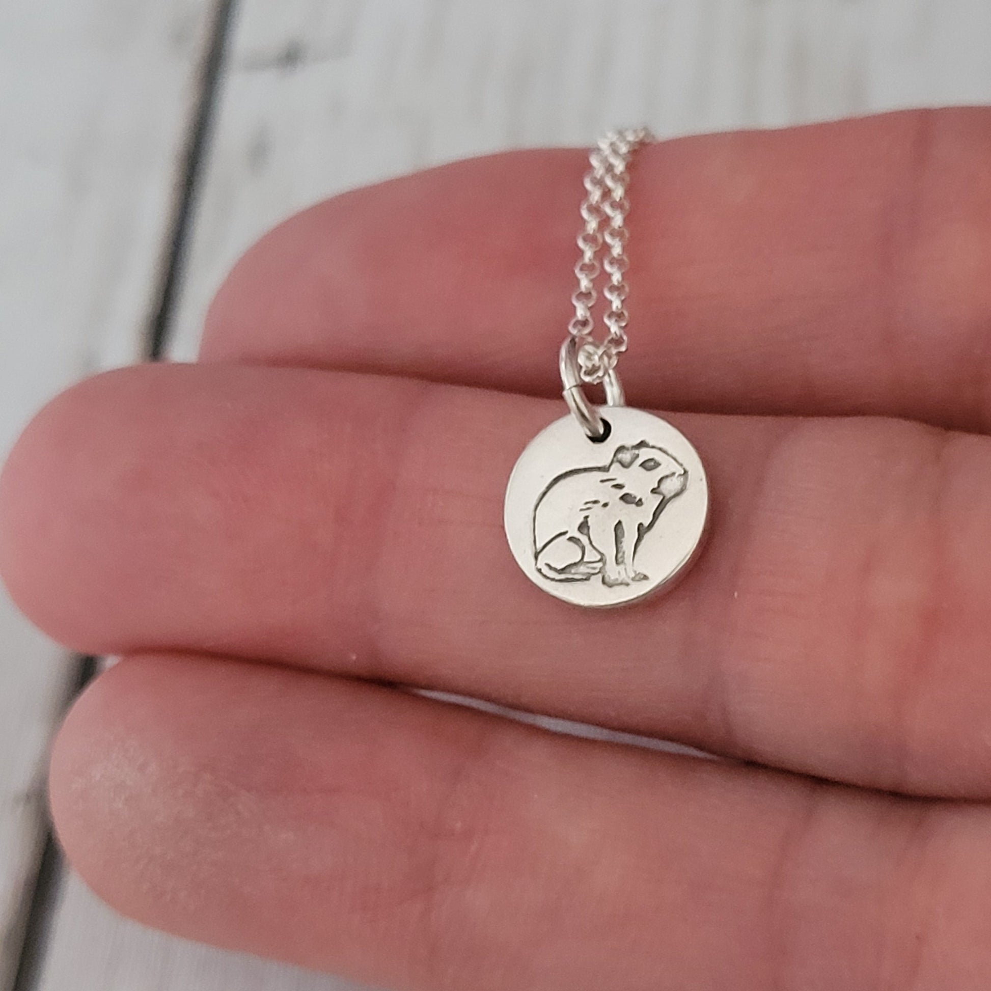 tiny 1cm capybara pendant being held in hand