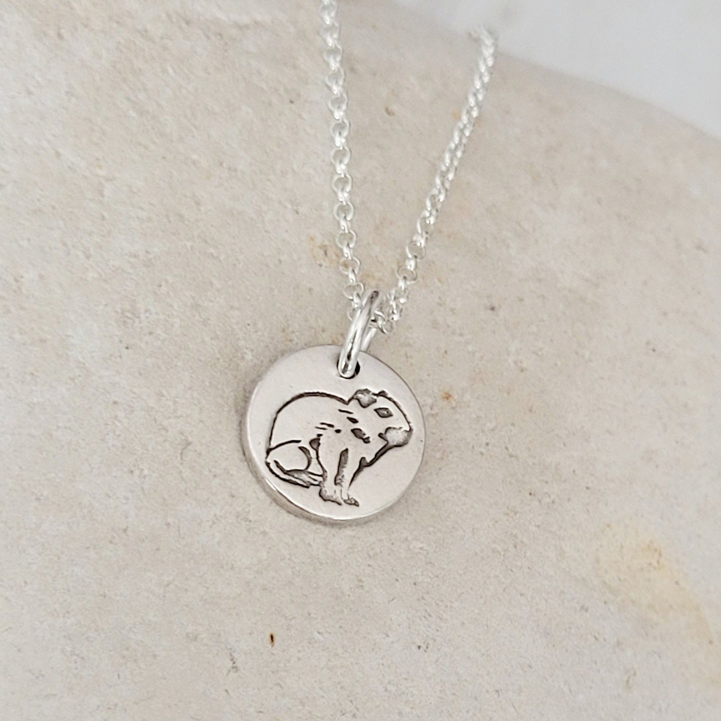 side view round capybara necklace on white stone