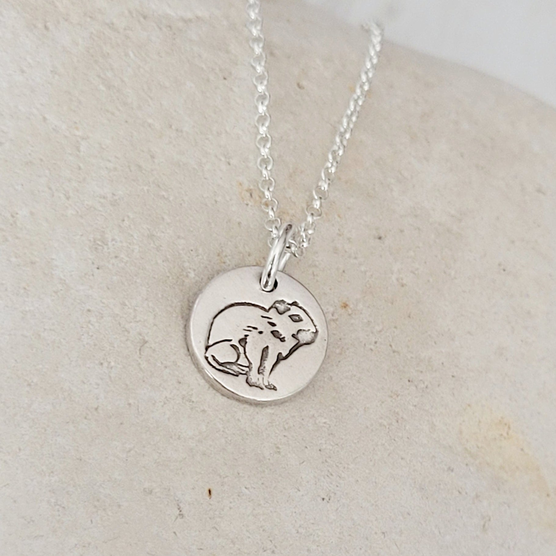 side view round capybara necklace on white stone