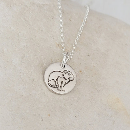 side view round capybara necklace on white stone