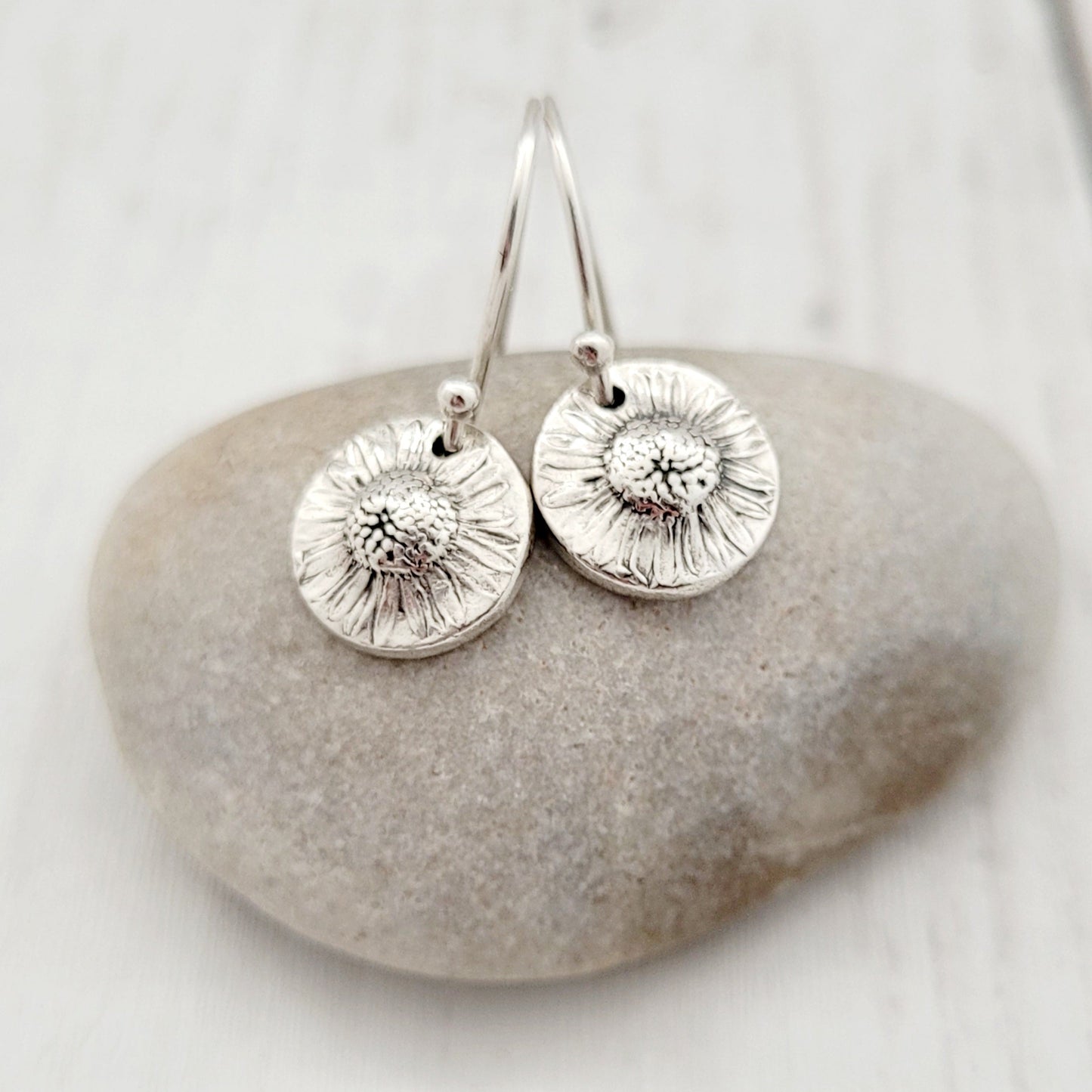 Silver earrings on a stone with a white background