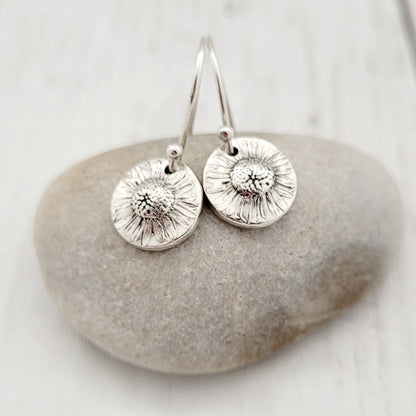 Silver earrings on a stone with a white background