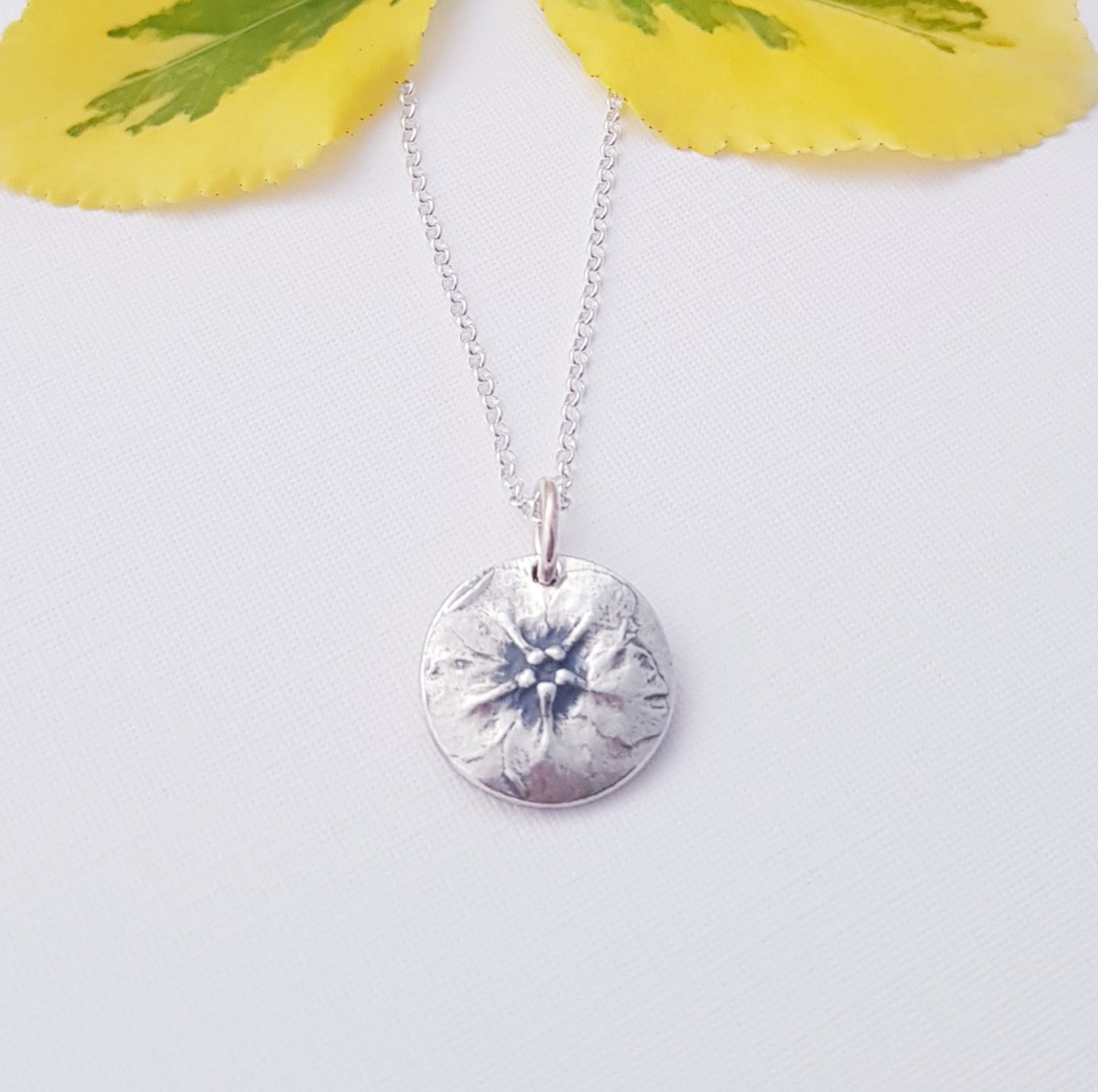 Silver green alkanet forget me not  round pendant on a light background