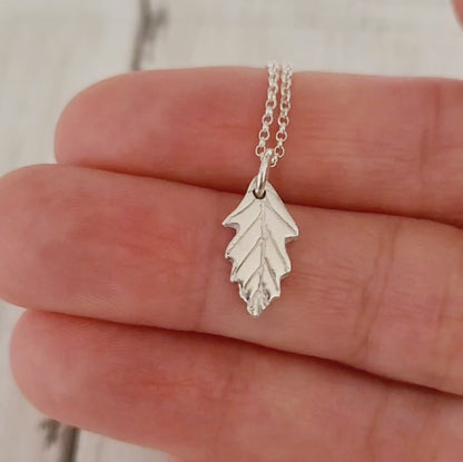 video silver tiny oak leaf necklace being held