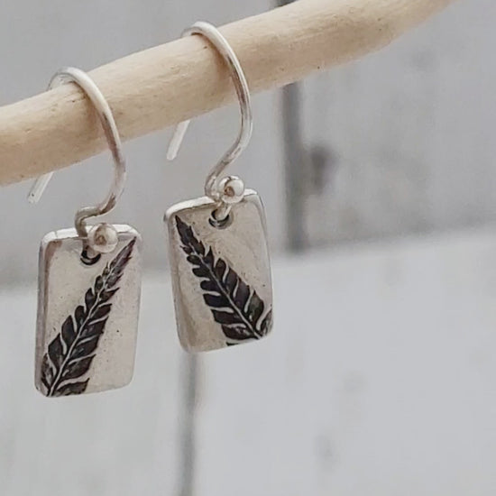 dainty rectangular fern leaf silver earrings hanging from twig