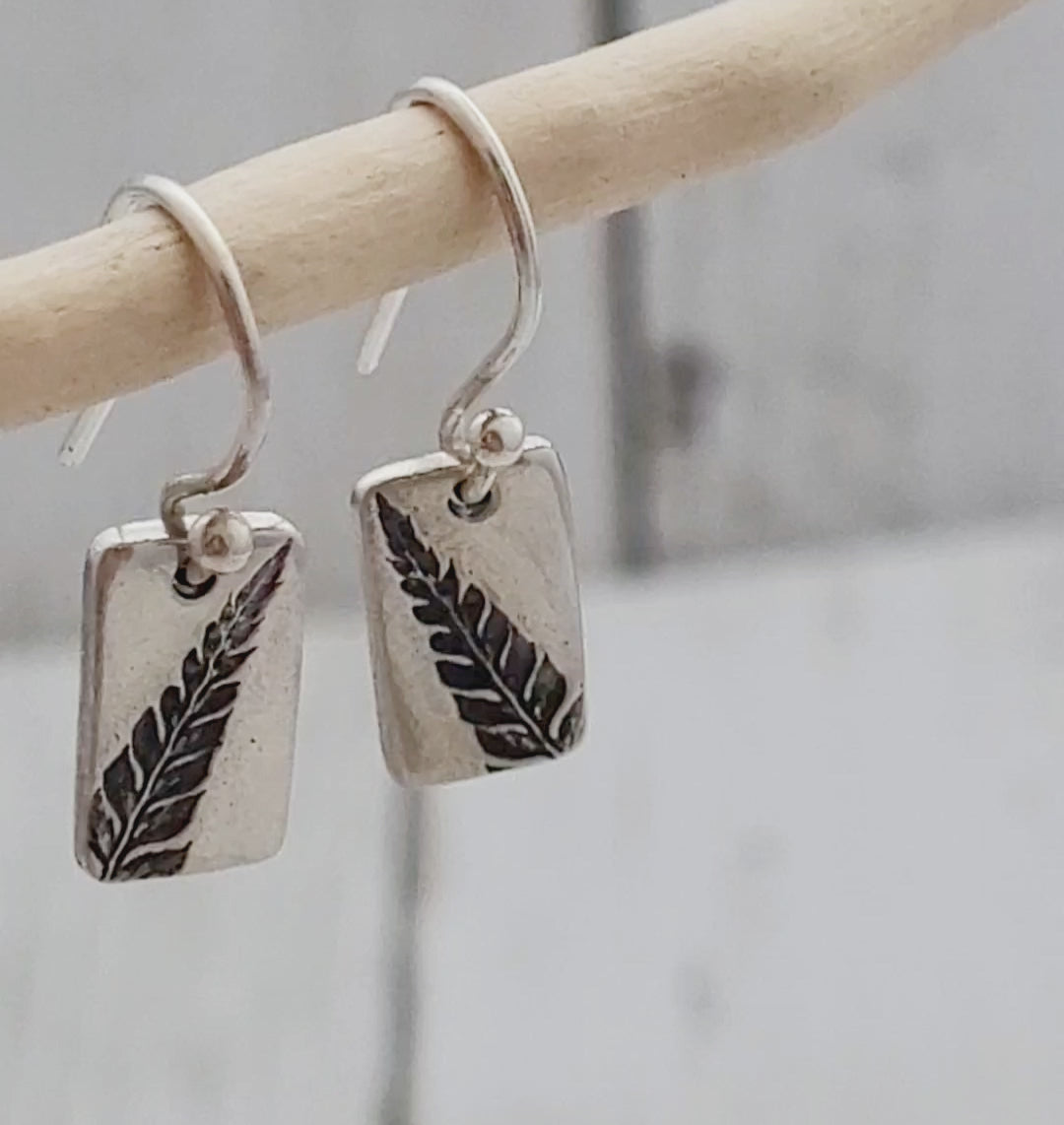 dainty rectangular fern leaf silver earrings hanging from twig