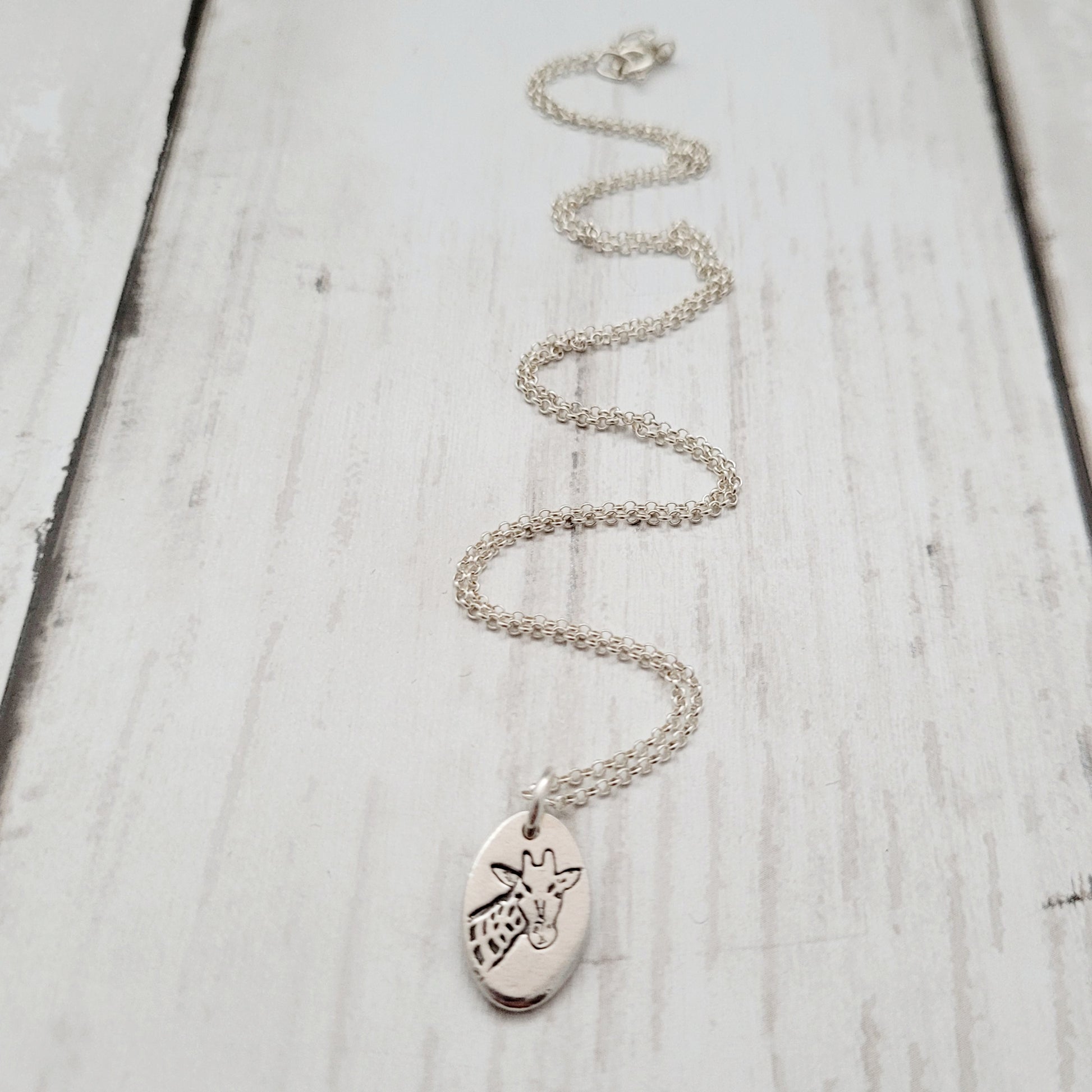Silver necklace with a pendant on a light wooden surface