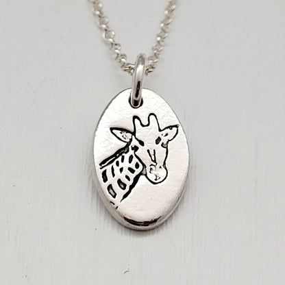 Silver pendant with a giraffe design on a light gray background