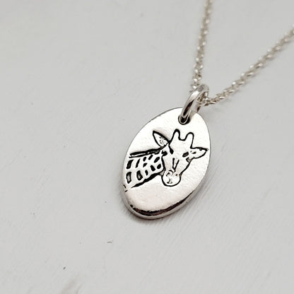 Silver necklace with a giraffe pendant on a light gray background