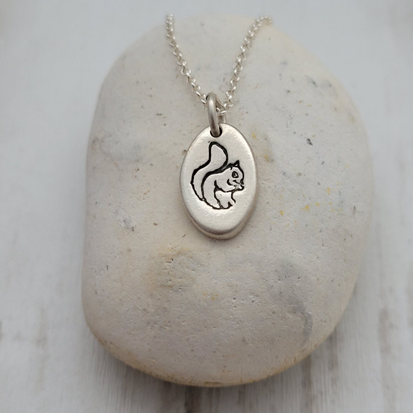 Silver necklace with a pendant on a stone surface