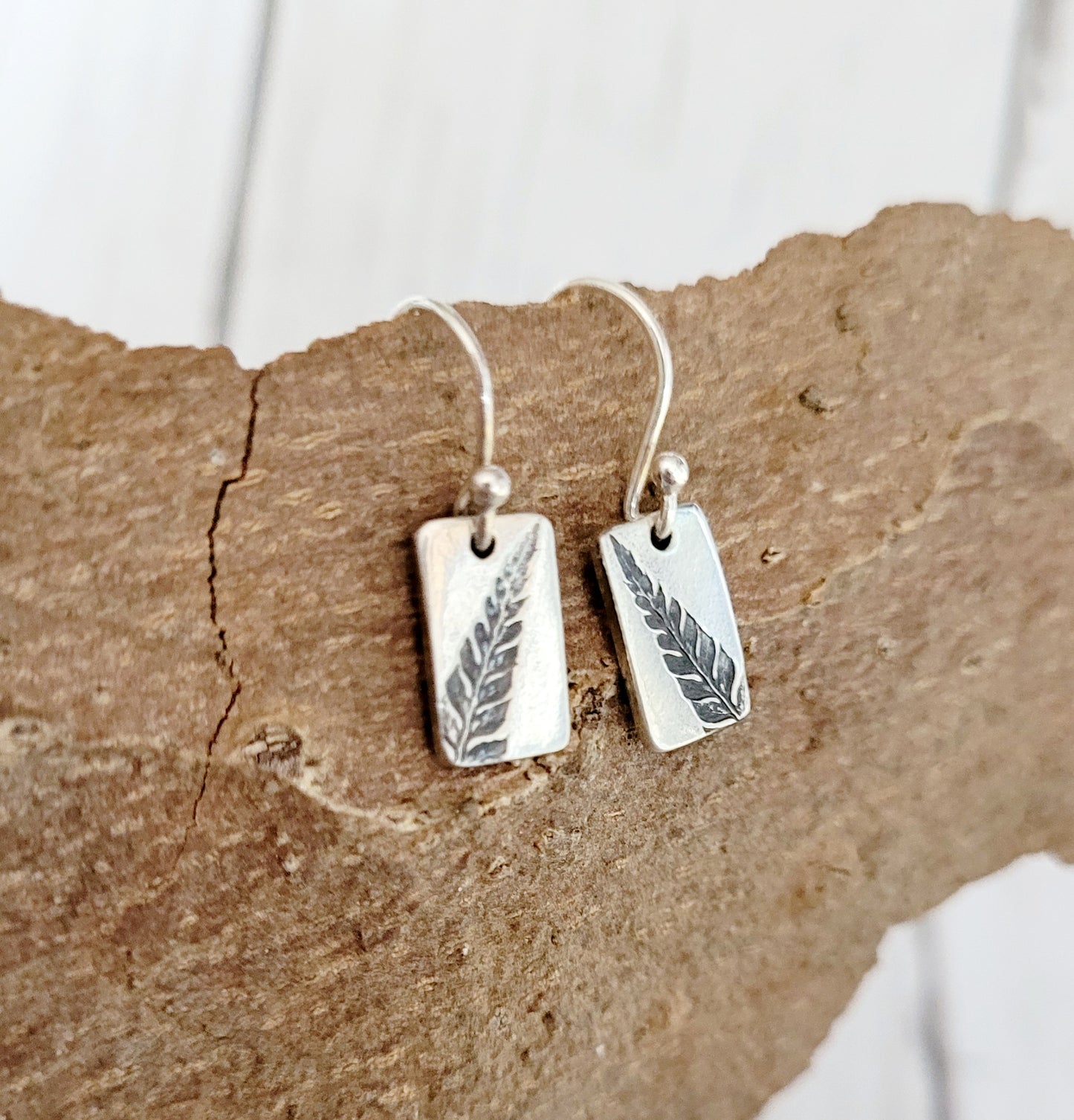 silver recatangular drop earrings with black fern leaf design