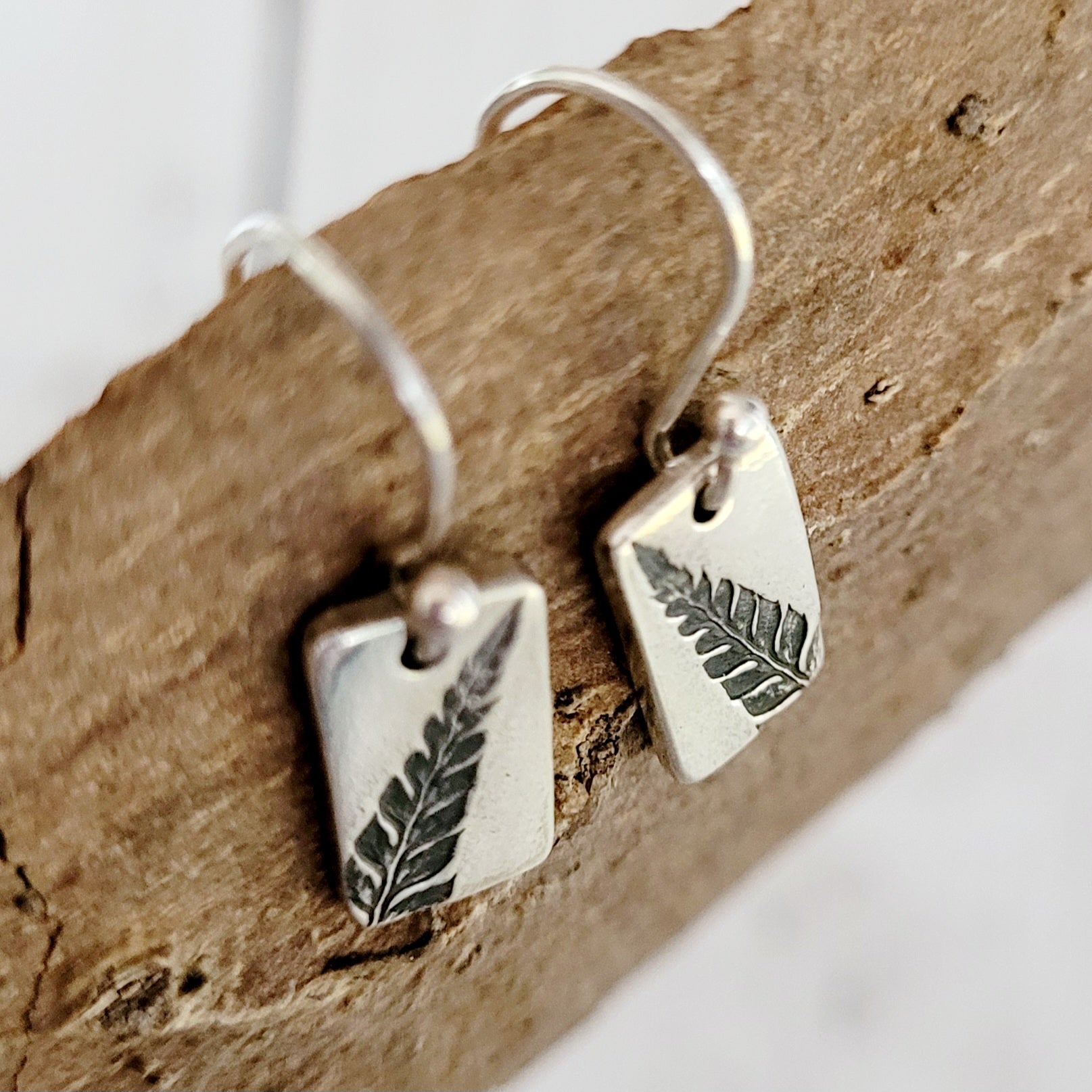 silver rectangle drop earrings with leaf design from above
