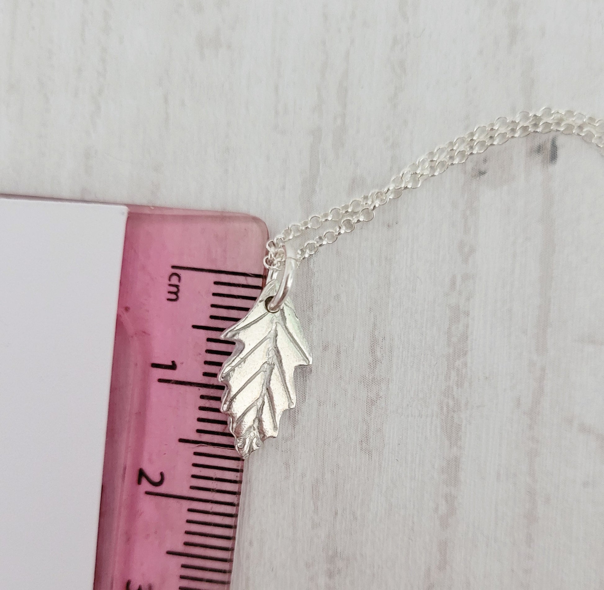 silver oak leaf necklace shown against ruler