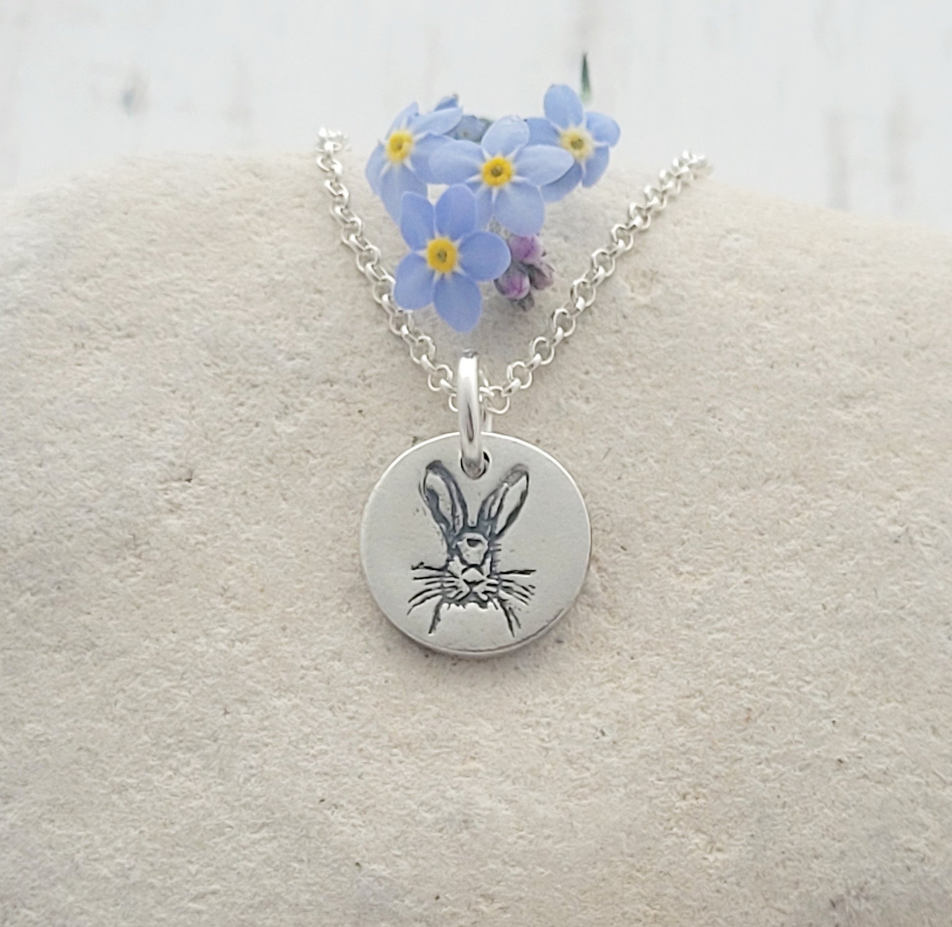 round animal pendant with blue flowers on white stome background