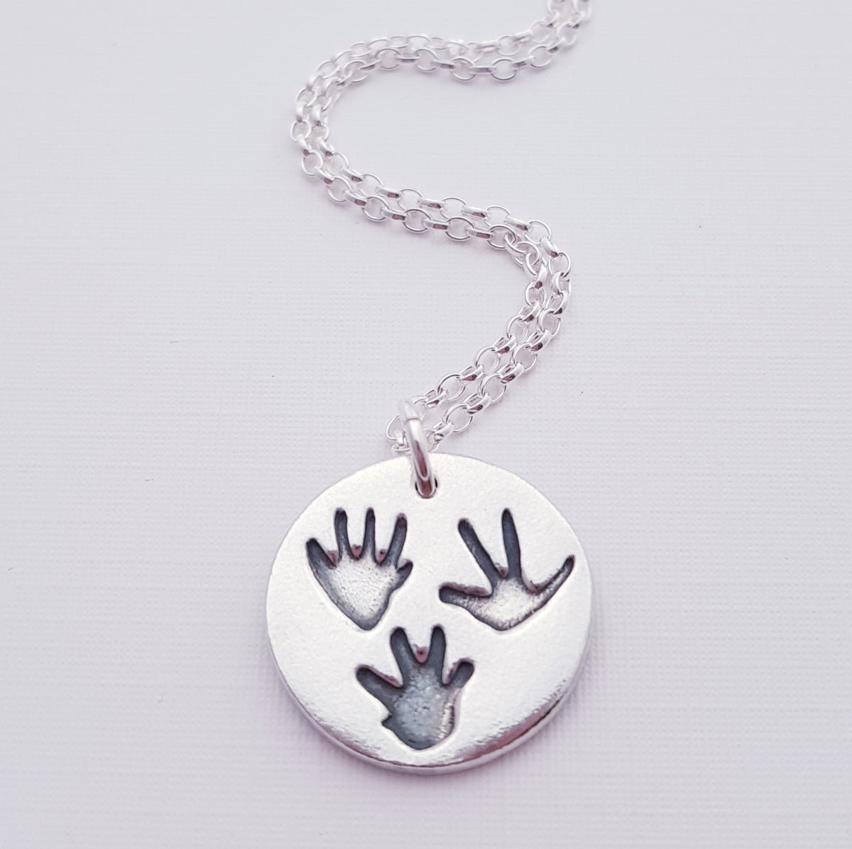 three tiny rat paw prints on a silver round pendant necklace
