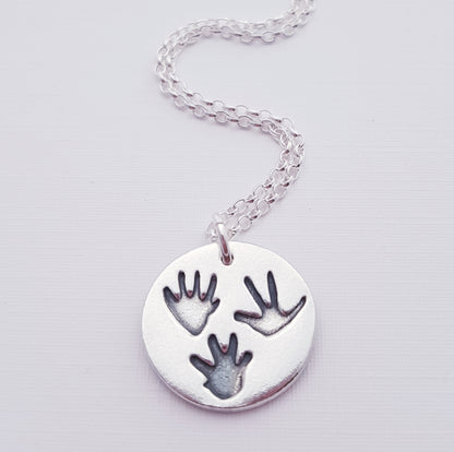 three tiny rat paw prints on a silver round pendant necklace