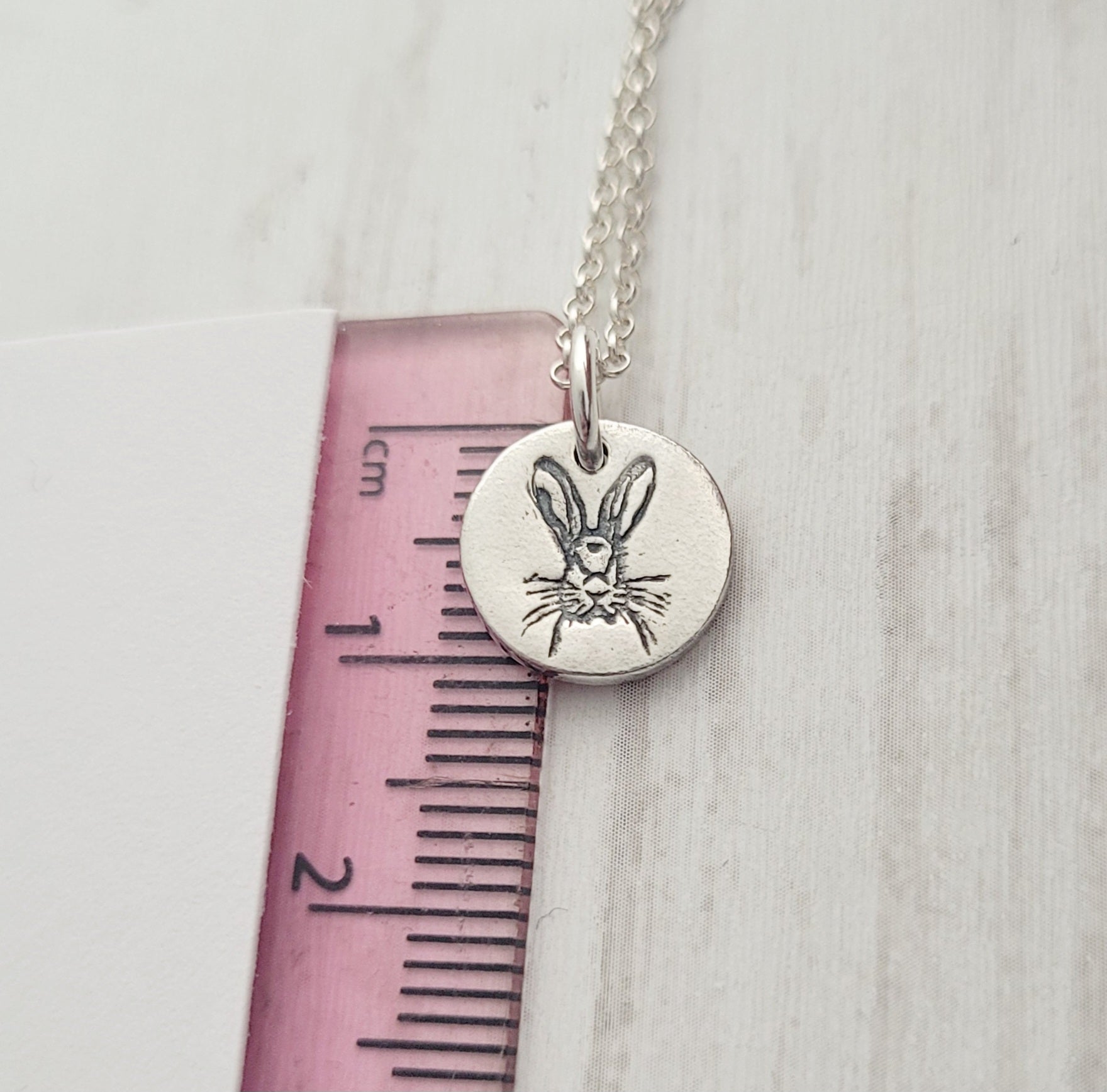 hare pendant against pink ruler