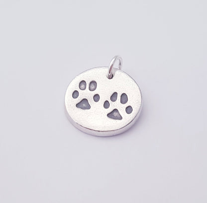 two black paw prints on a round pendant charm